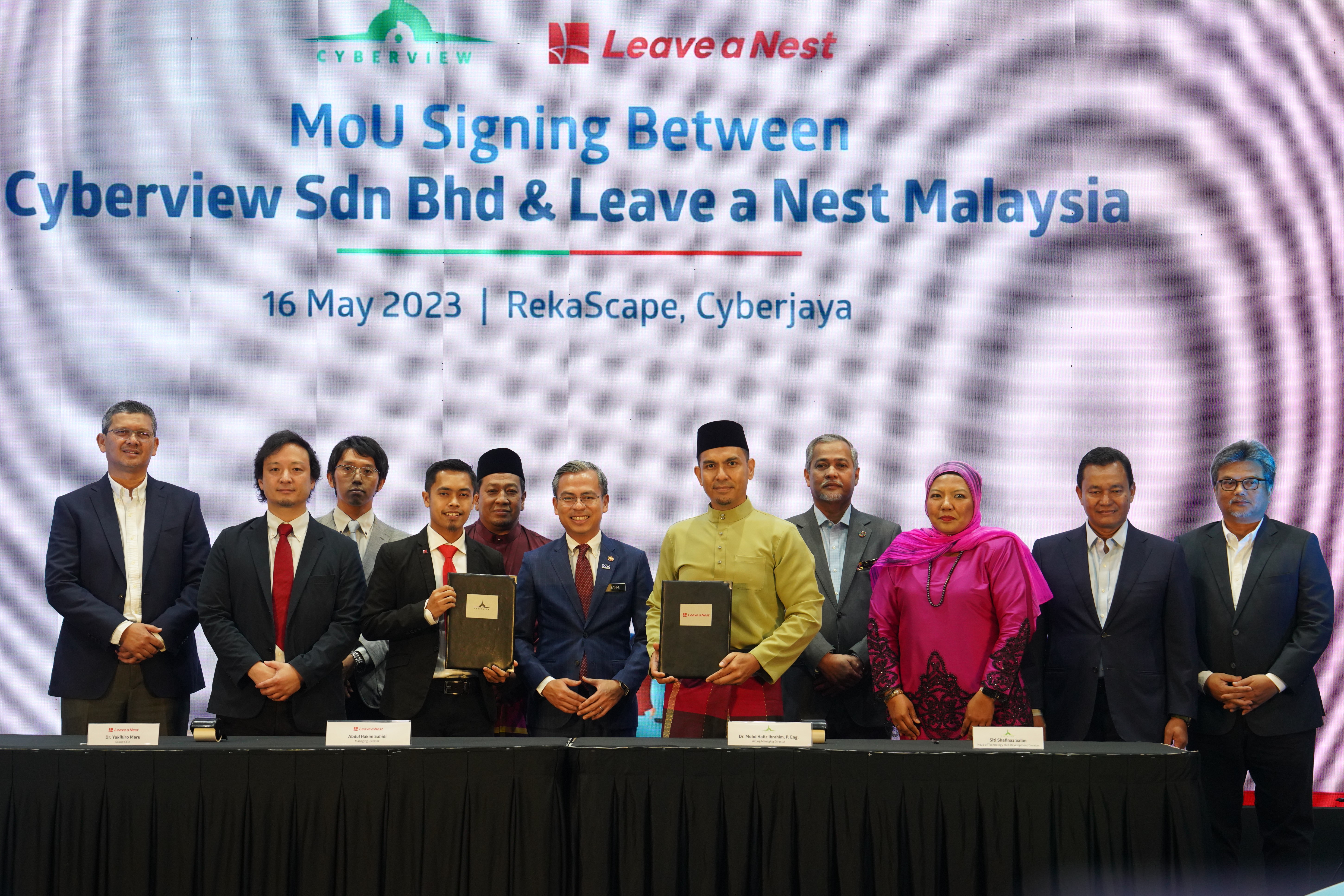 Pengarah Urusan Leave A Nest Malaysia, Abdul Hakim Sahidi (empat dari kiri) dan Mohd Hafiz (lima dari kanan) pada majlis menandatangani MoU disaksikan oleh Fahmi (tengah).