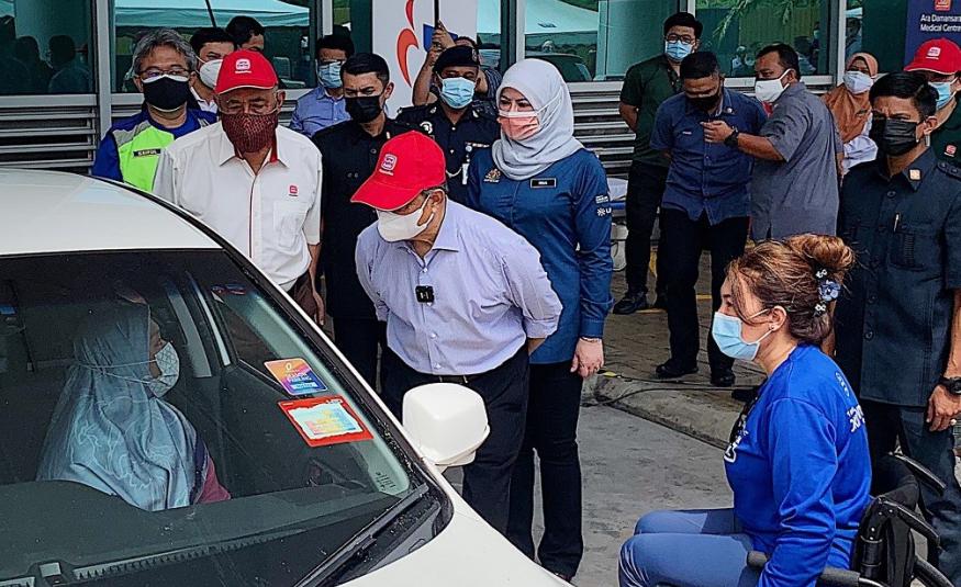 Muhyiddin ketika menyantuni komuniti OKU yang mendapatkan vaksinasi di PPV pandu lalu di Ara Damansara.