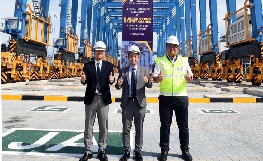 (Dari kiri ke kanan) Atsufumi Takahashi, Saito Hiroaki dan Azman Shah Mohd Yusof berdiri di hadapan kren Rubber Tyred Gantry ketika upacara penyerahan rasmi peralatan terminal baharu tersebut pada 8 Februari 2023.