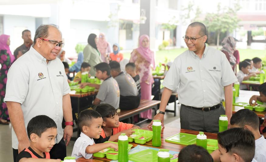 Nor Azman Zainal (kanan) dan Ketua Pegawai Eksekutif Takaful Malaysia Am, Mohamed Sabri Ramli (kiri) menyantuni pelajar SK Seri Bonus pada majlis Di Hatiku Student Food Aid Program di Kuala Lumpur.